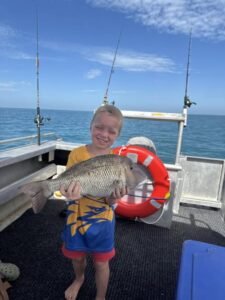 Young boy from the King family holding a black snapper on a Shark Bay fishing adventure with Monkey Mia Boat Hire.