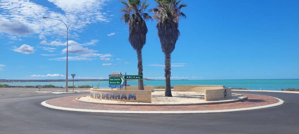 Welcome to Denham roundabout overlooking Shark Bay, with signs to Monkey Mia and the town centre – gateway to Monkey Mia Boat Hire Shark Bay adventures.